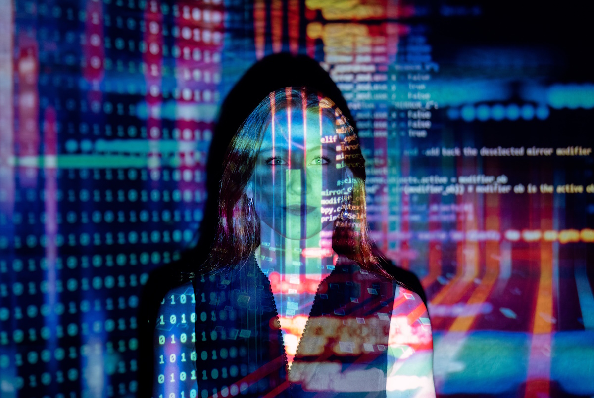 A woman stands with an image of computer code projected onto her.