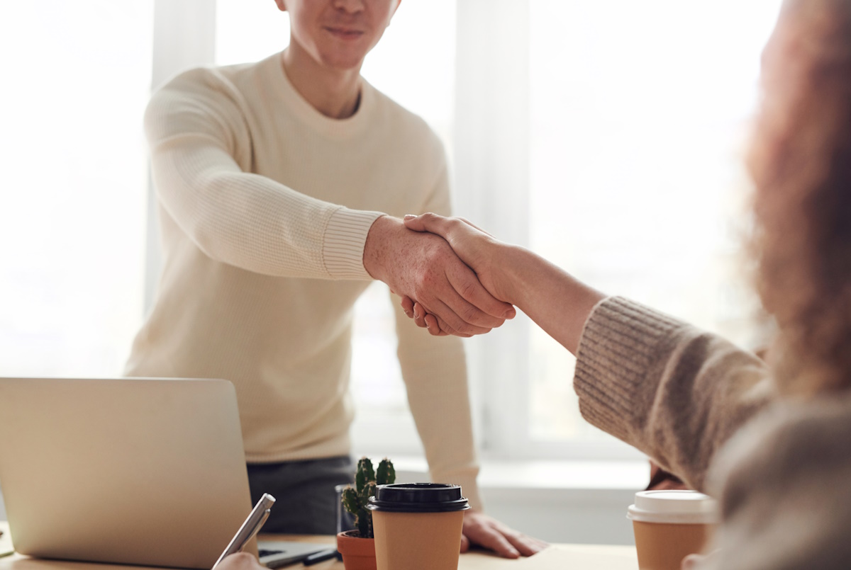 Two people shake hands in a cozy office setting.